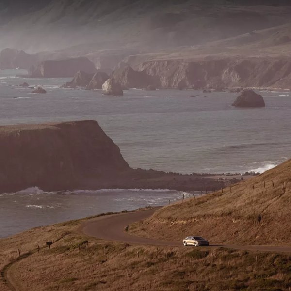 A Lucid Air driving on a coastal winding road.